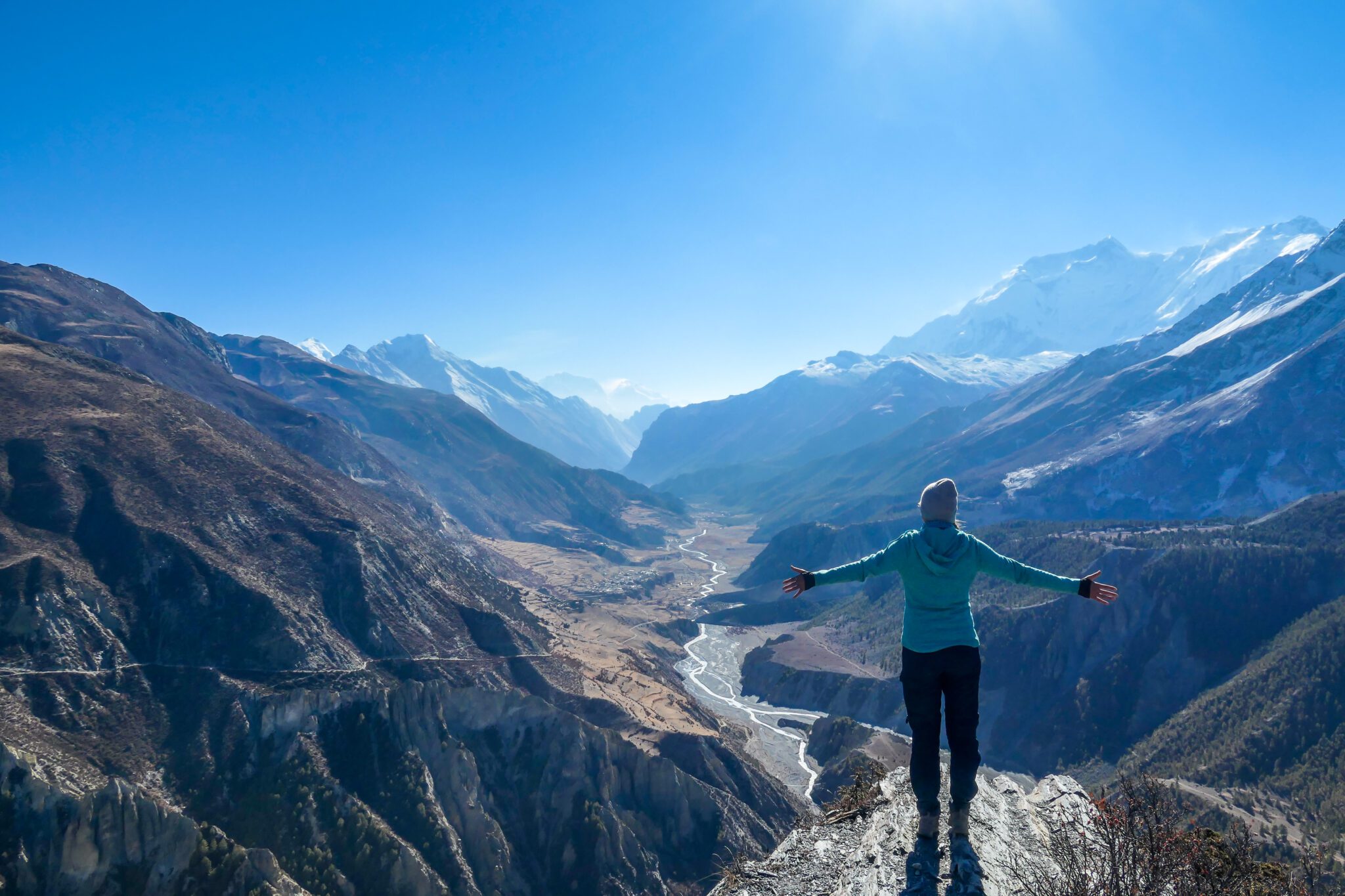 Nepal - Girl spreads her hands wide, Manang Valley A person standing on top of a mountain with arms outstretched.