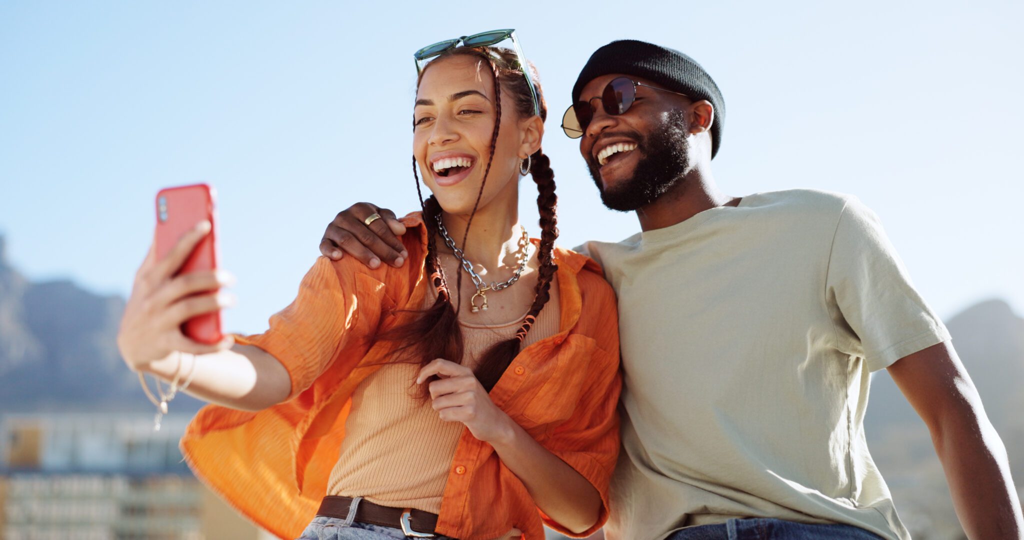Couple, bonding and phone selfie on city building rooftop on New York summer holiday, travel vacation date or social media memory. Smile, happy or black man and woman on mobile photography technology A man and woman are smiling for the camera.