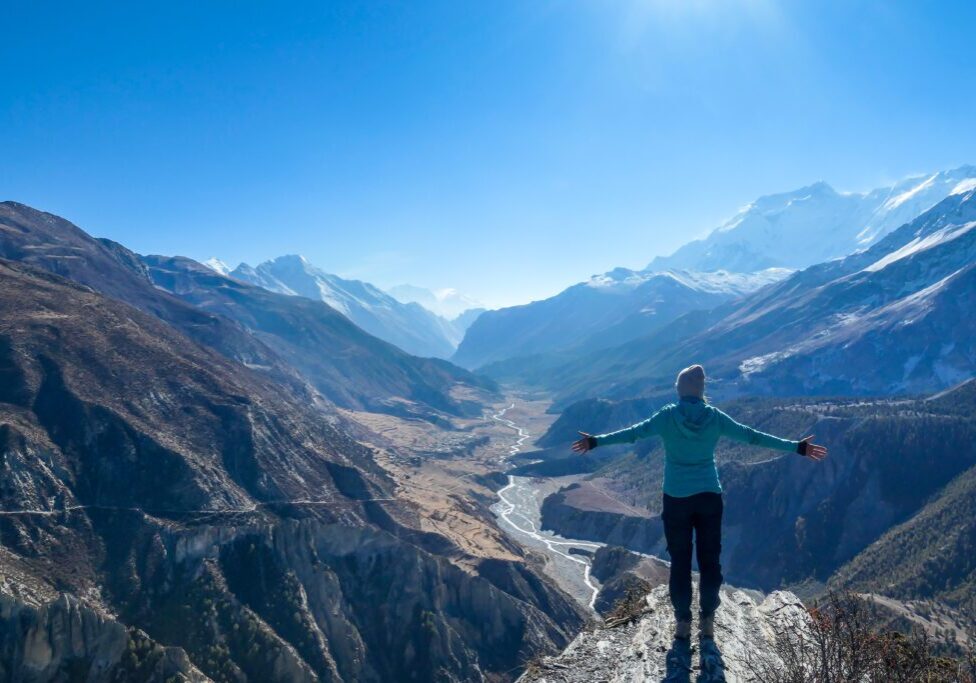 A person standing on top of a mountain with arms outstretched.