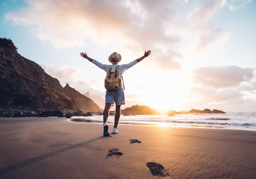 A person standing on the beach with their arms outstretched.