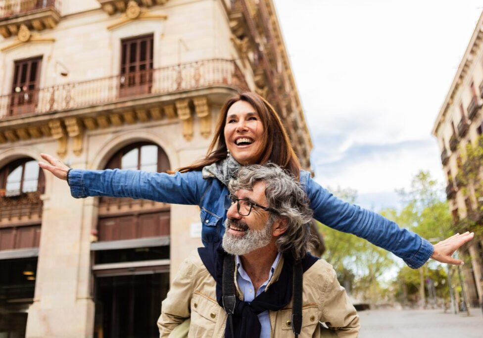 A woman is riding on the back of an older man.