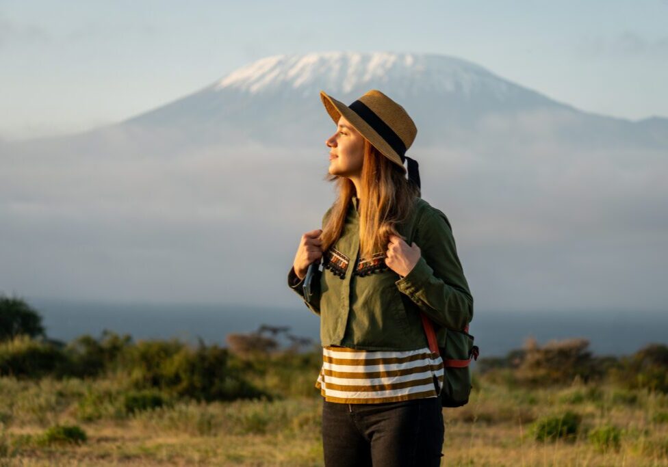 A woman in a hat and jacket standing on the grass.