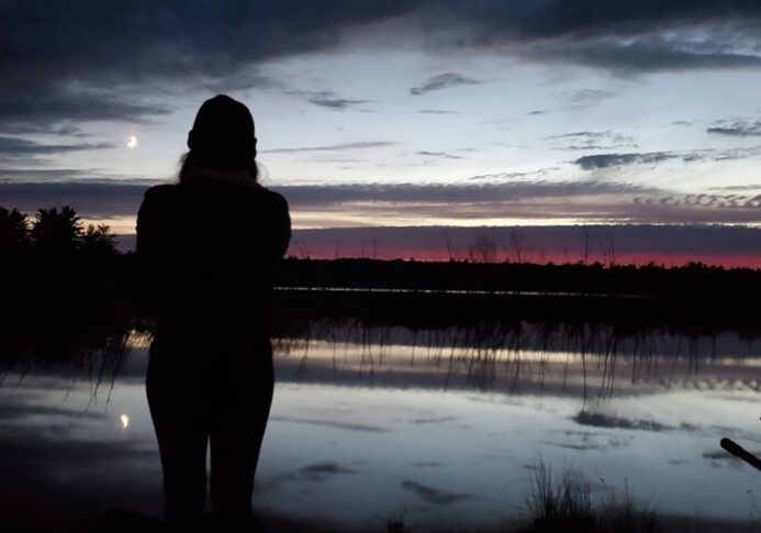 ty45 A woman standing in front of the water at dusk.